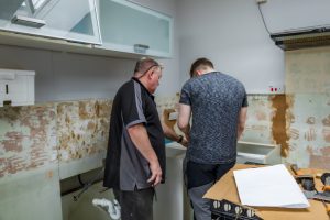 two men are working away in the kitchen and refurbishing it