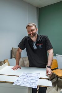 a man is standing inside our kitchen refurbishment and smiling at the camera