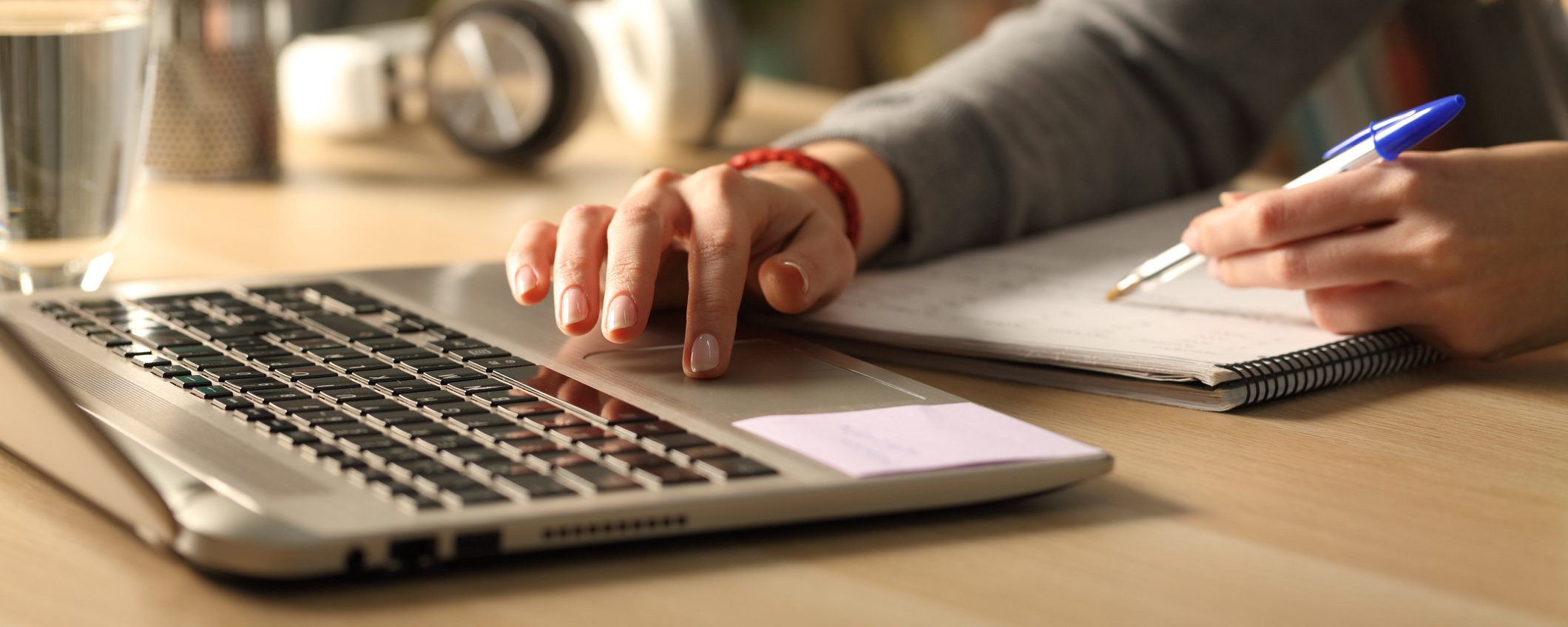 the photo shows a person sitting indoors at a desk using their laptop